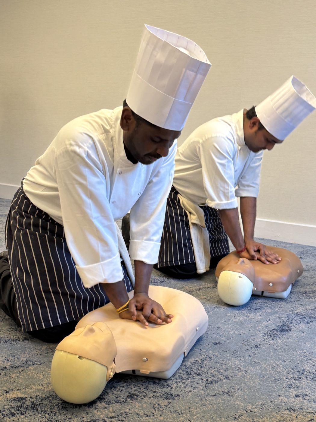 Chefs practising chest compressions on CPR manikins