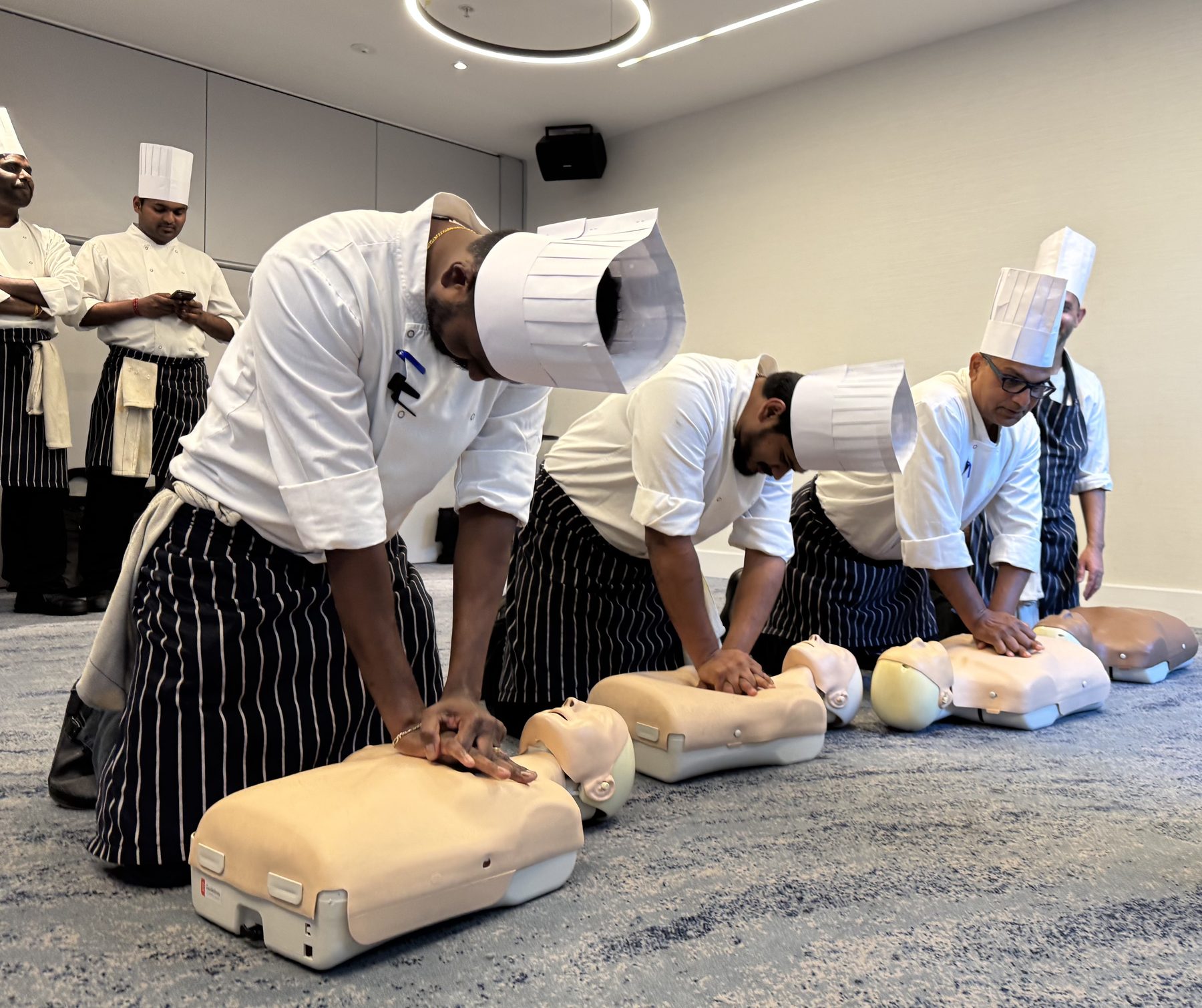 Chefs practising CPR on manikins during on-site first aid training